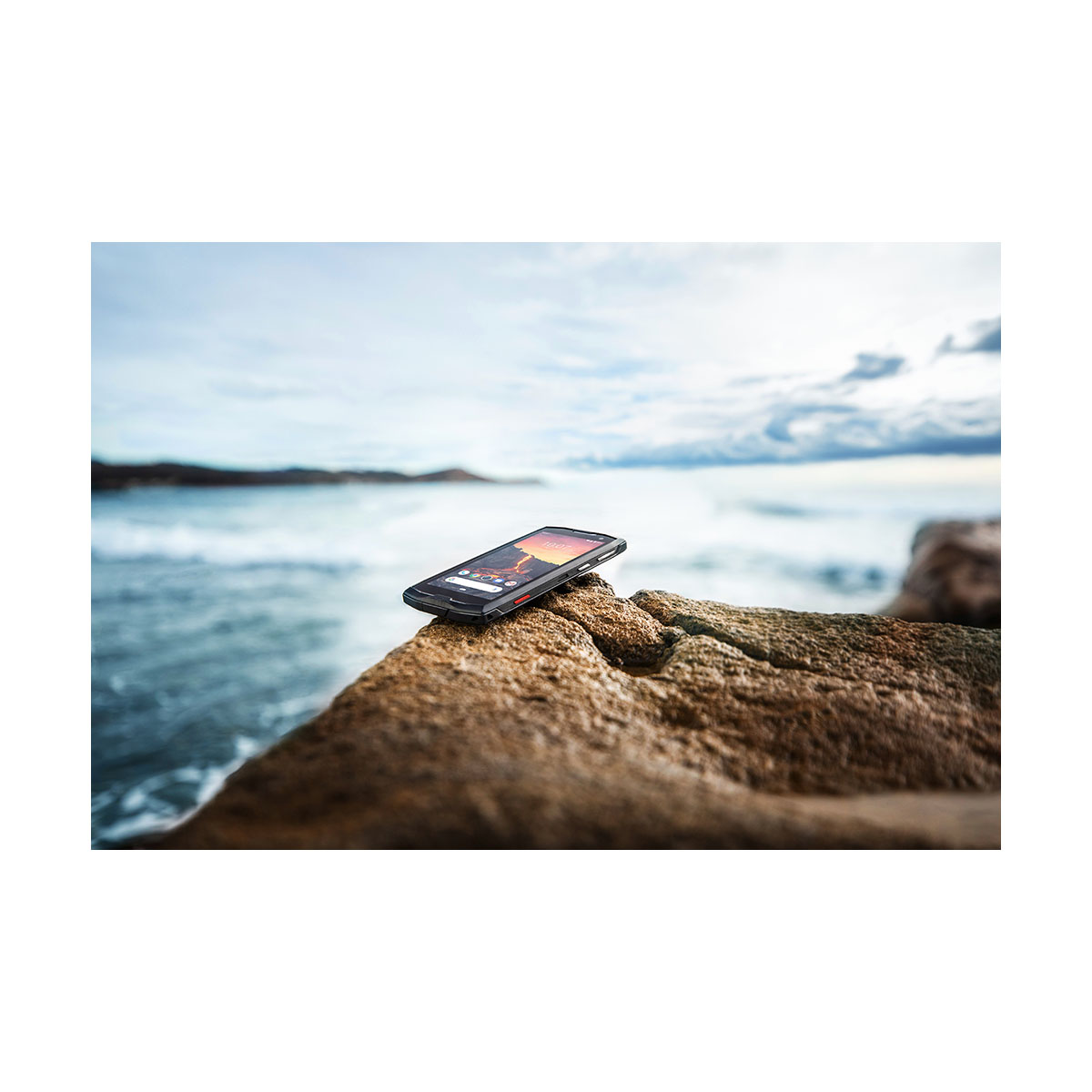 Smartphone sur un rocher près de l'océan. Ciel, eau et rochers visibles.
