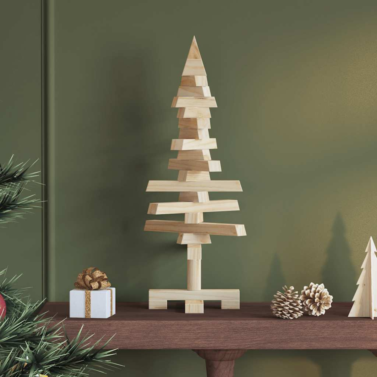 Ein Weihnachtsbaum aus Holz auf einem Regal, mit Geschenk und Tannenzapfen. Baum aus Holzblöcken.