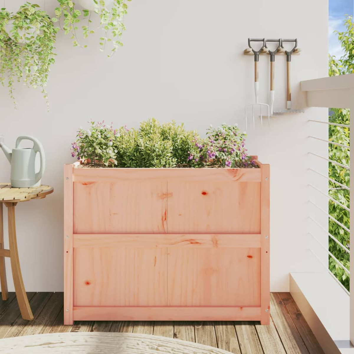 Ein Holzpflanzer auf einem Deck mit Pflanzen und Gartengeräten. Eine Gießkanne steht auf einem kleinen Tisch.