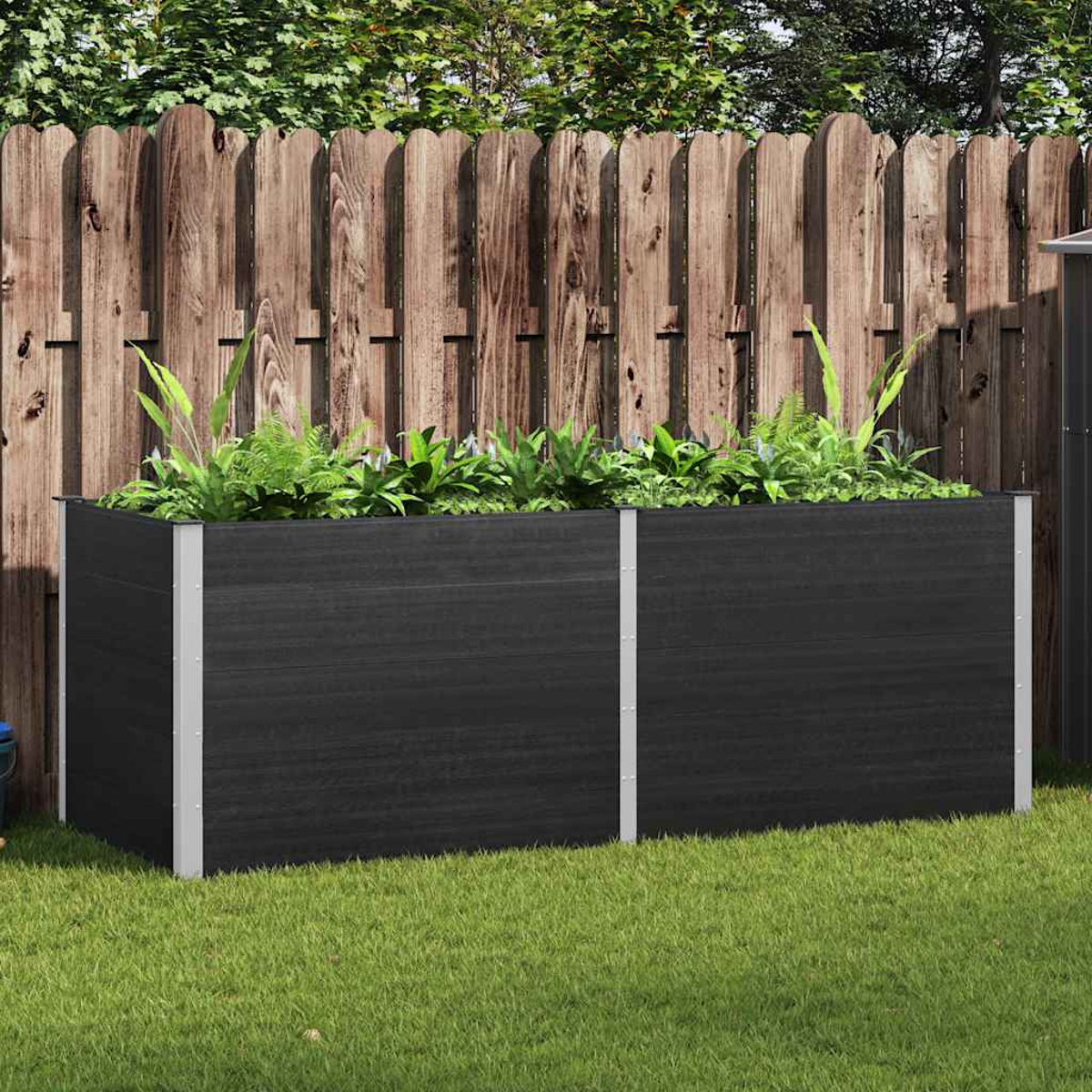 Pflanzkasten mit Pflanzen in einem Garten. Schwarze Box vor Holzzaun und Gras.