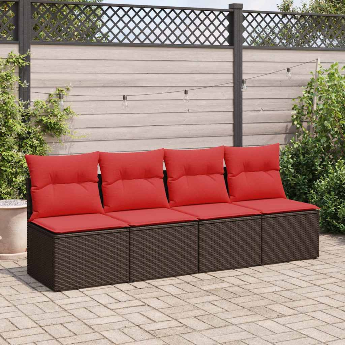 Ein braunes Outdoor-Sofa aus Korbgeflecht mit roten Kissen, vor einem Zaun.