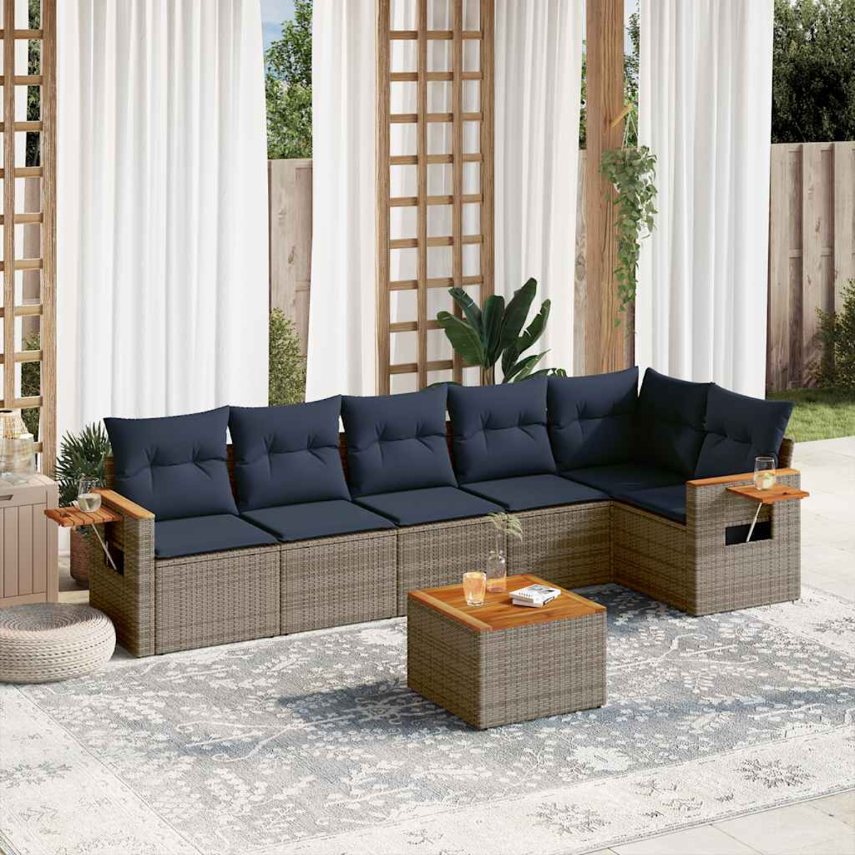 Ein graues Rattan-Ecksofa mit blauen Kissen, einem Couchtisch aus Holz, draußen mit weißen Vorhängen.