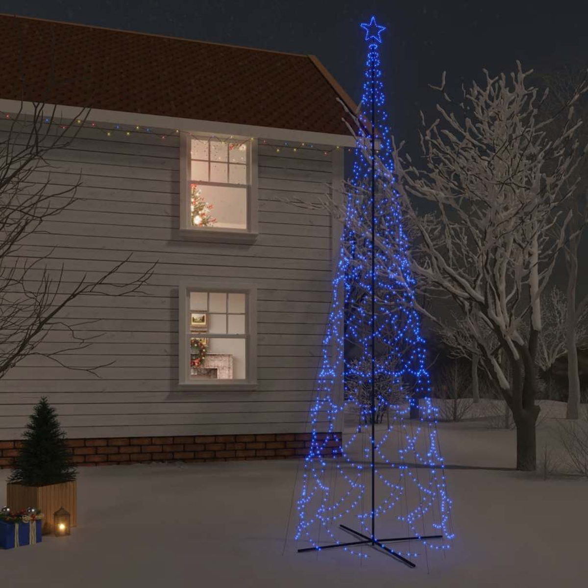 Eine nächtliche Außenszene mit einem beleuchteten blauen Weihnachtsbaum im Schnee und einem Haus im Hintergrund.