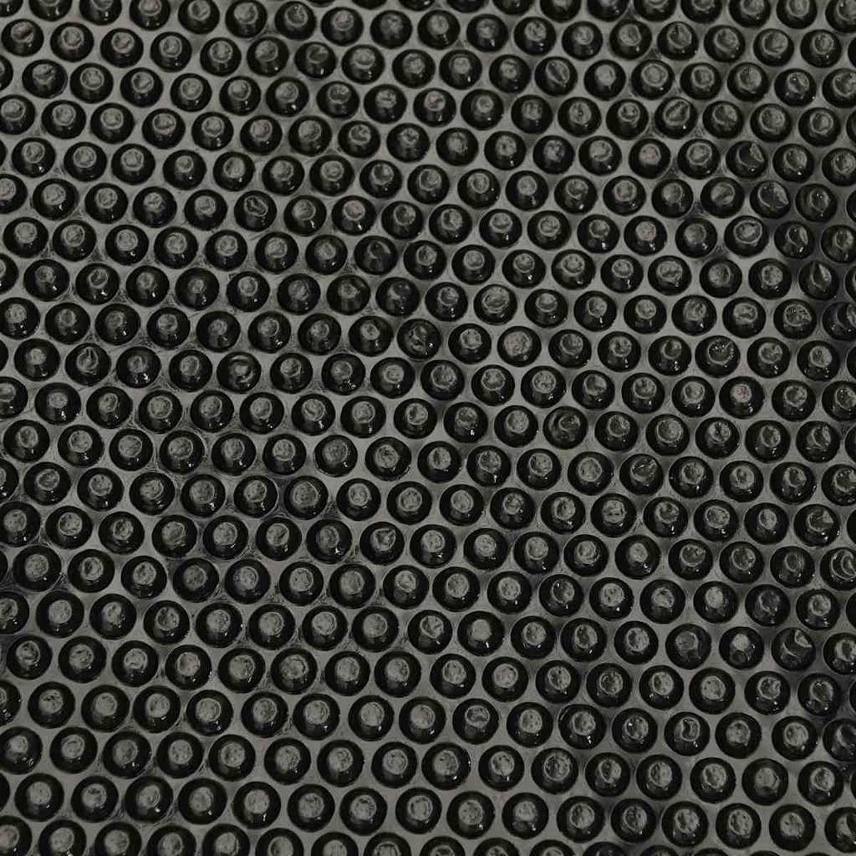 Nahaufnahme einer schwarzen, strukturierten Oberfläche mit gleichmäßig verteilten, kleinen, kreisförmigen Erhebungen. Keine weiteren Details.