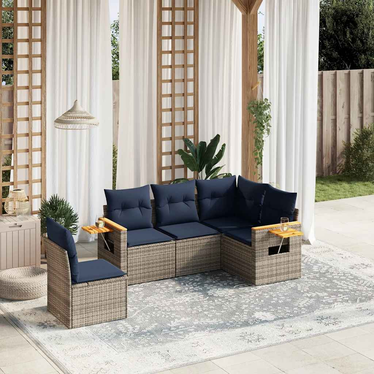 Outdoor-Korbsessel-Set mit blauen Kissen. Beinhaltet ein Sofa, einen Stuhl und einen gemusterten Teppich. Die Szene ist im Freien.