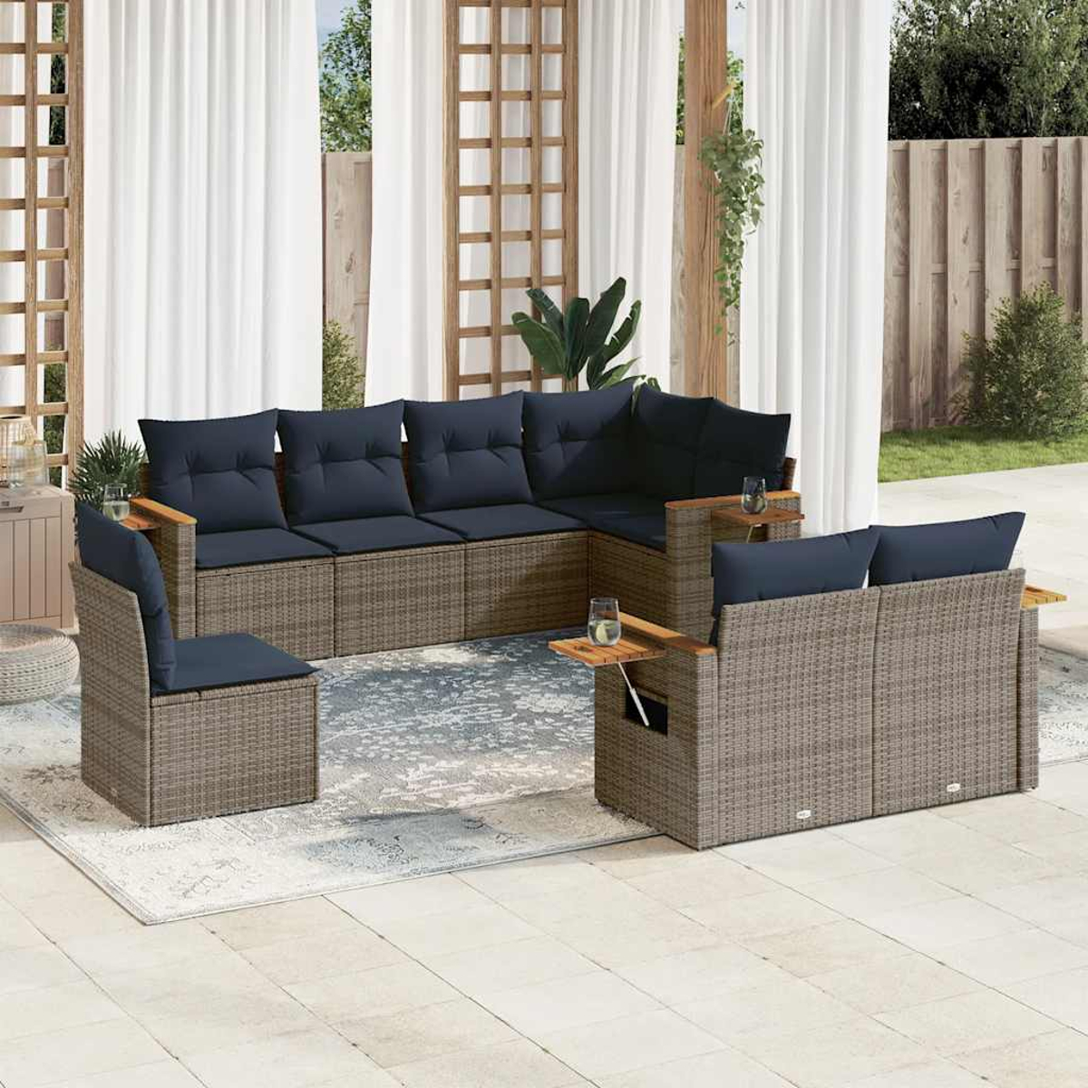 Ein Rattan-Gartenmöbel-Set mit blauen Kissen auf einer Terrasse. Enthält ein Sofa und Stühle.
