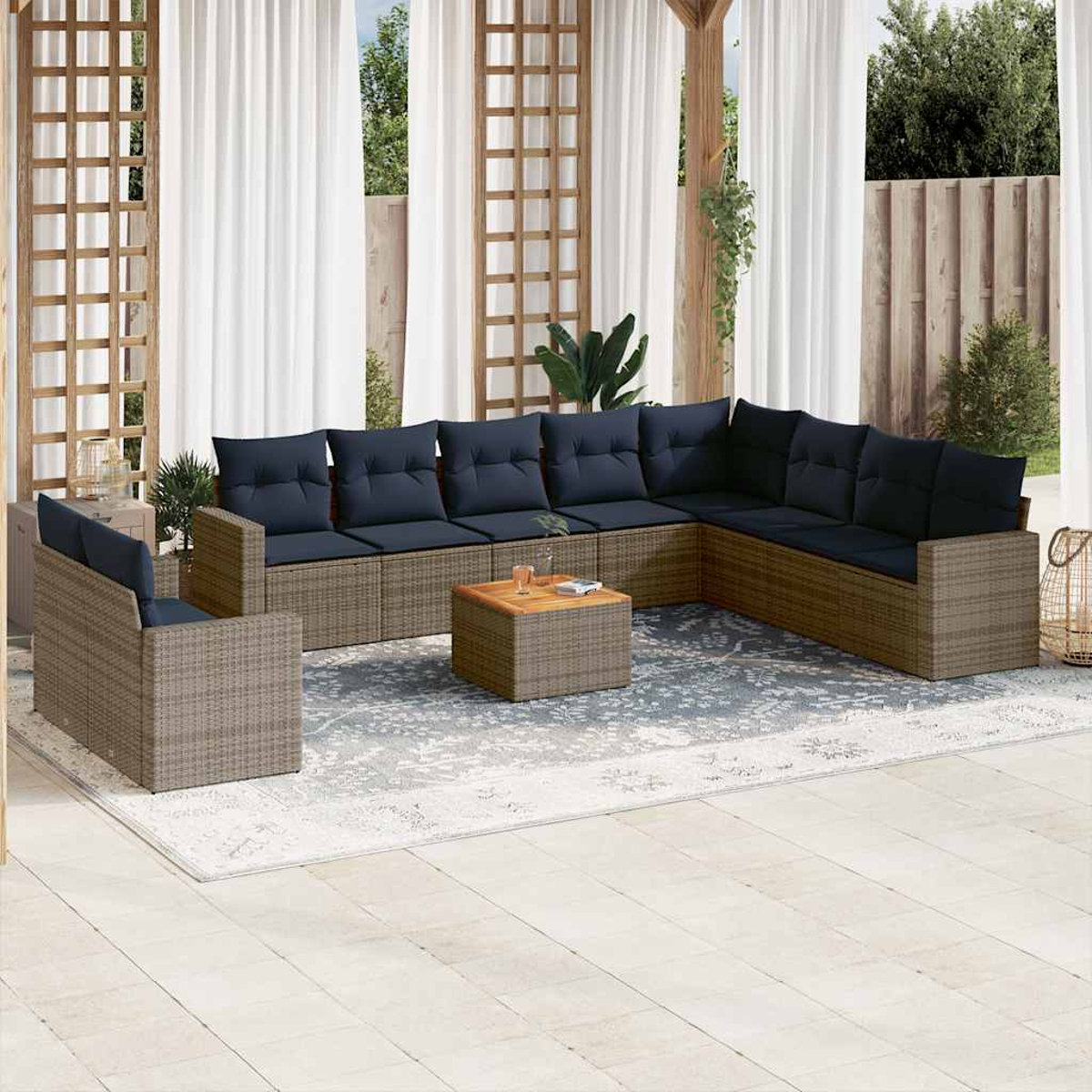 Eine Außenterrasse mit einem großen grauen Ecksofa mit blauen Kissen und einem Tisch.