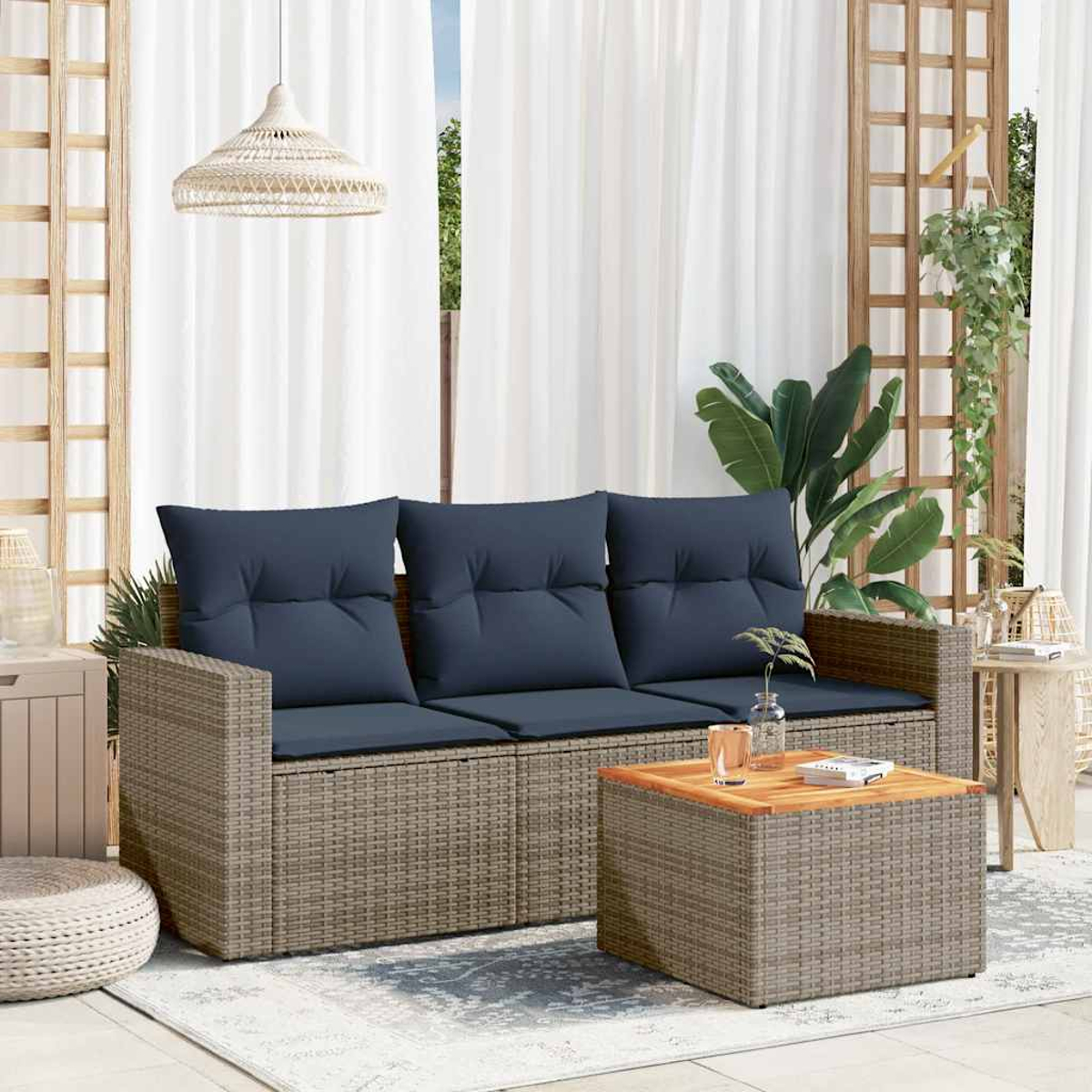 Ein beiges Korbmöbelsofa mit drei marineblauen Kissen. Ein Couchtisch und ein weißer Vorhanghintergrund.