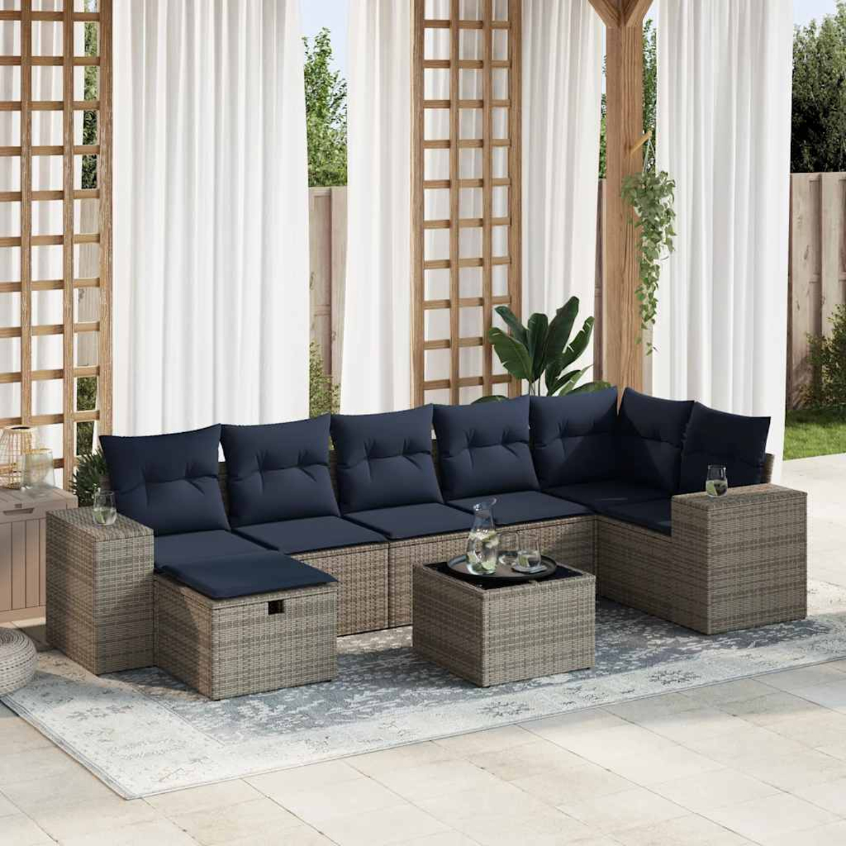 Ein graues Rattan-Ecksofa mit marinefarbenen Kissen und einem Tisch mit Glasplatte.