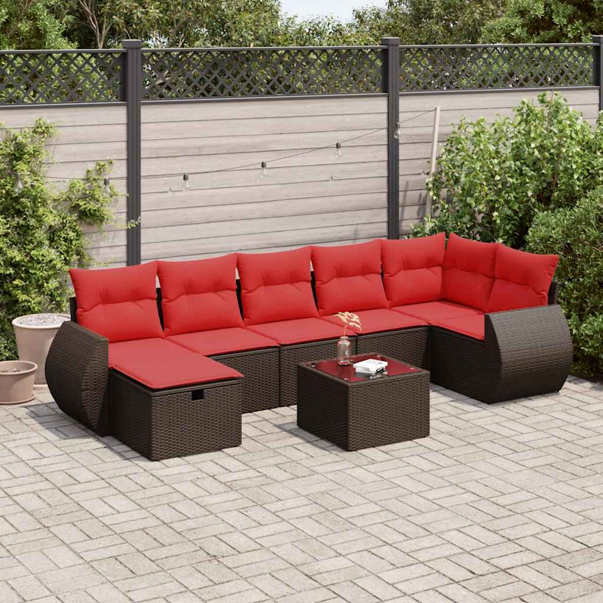 Eine Sitzgruppe für den Außenbereich mit dunkelbraunem Korbgeflecht und roten Kissen. Enthält einen Couchtisch.