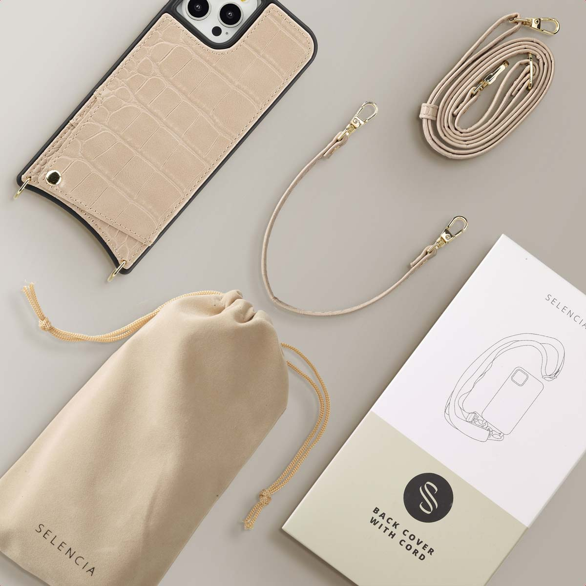 Een telefoonhoesje, een beige draagtas, een koord en een doos met een tekening van een telefoon.