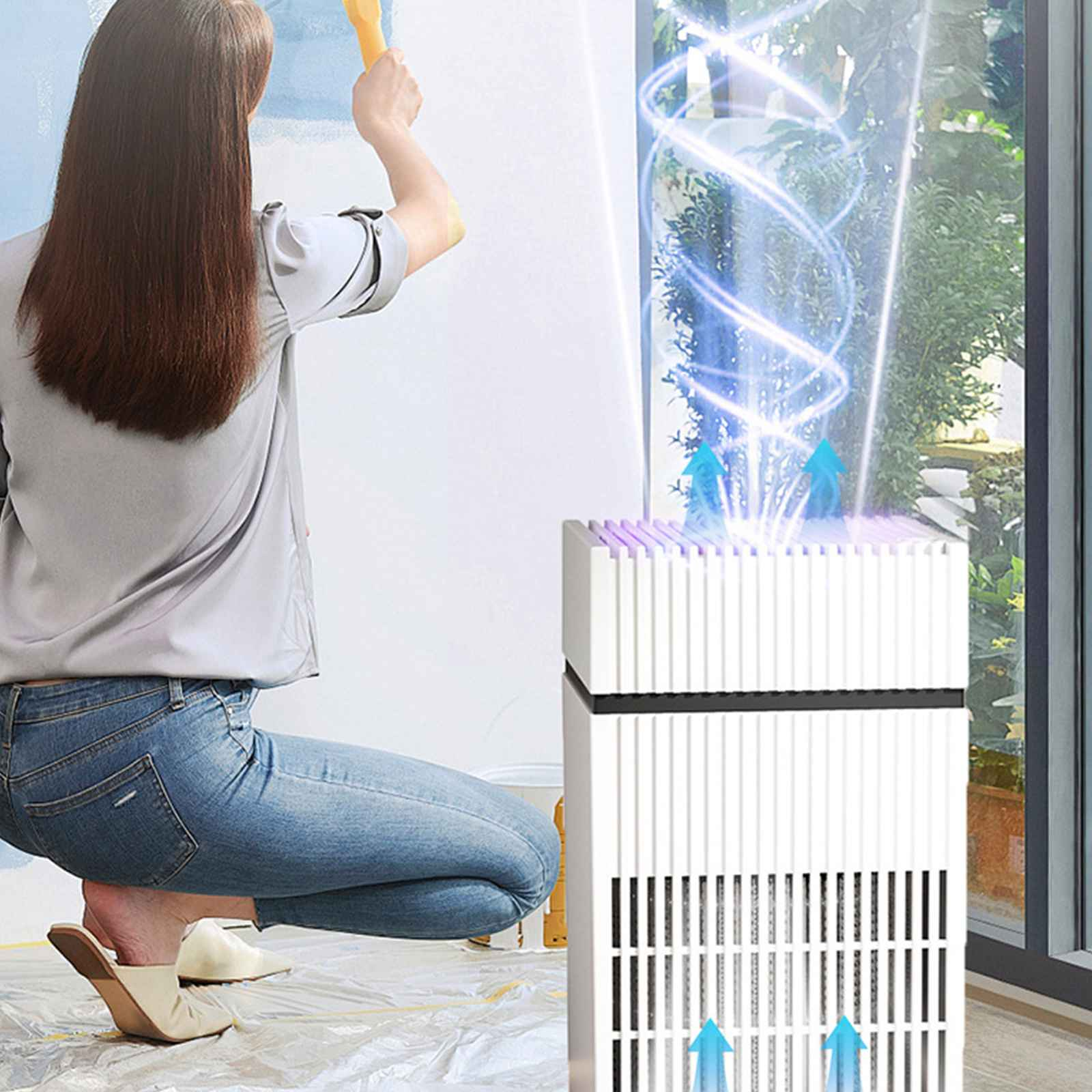 Eine Frau streicht eine Wand neben einem Luftreiniger in einem Raum mit einem großen Fenster.