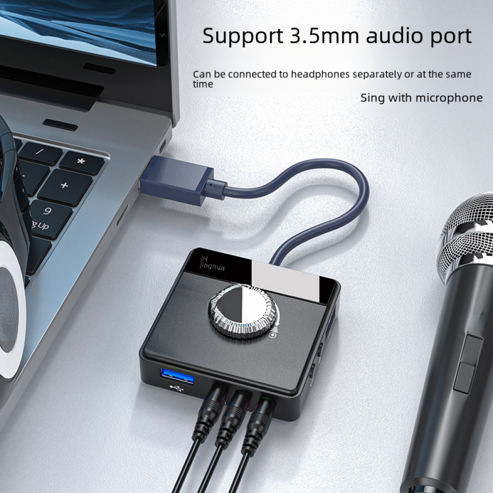 Ein schwarzer Audio-Umschalter, der an einen Laptop angeschlossen ist. Es zeigt USB-Anschlüsse und einen silbernen Lautstärkeregler.