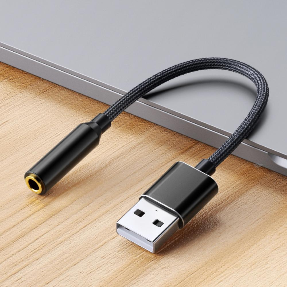 USB-zu-3,5-mm-Audiokabel. Schwarze Anschlüsse und Kabel. Hintergrund aus Holzoberfläche.