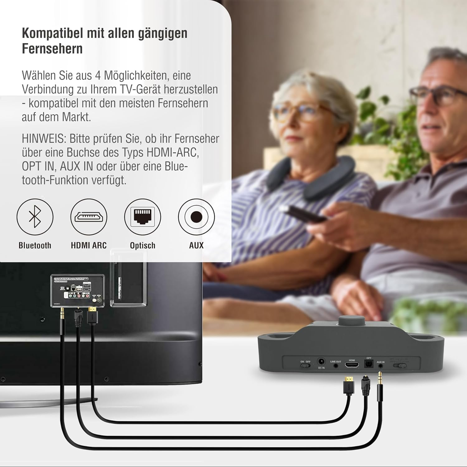 Zwei ältere Menschen mit Nackenlautsprecher, die fernsehen. Kabel und ein Gerät sind sichtbar.