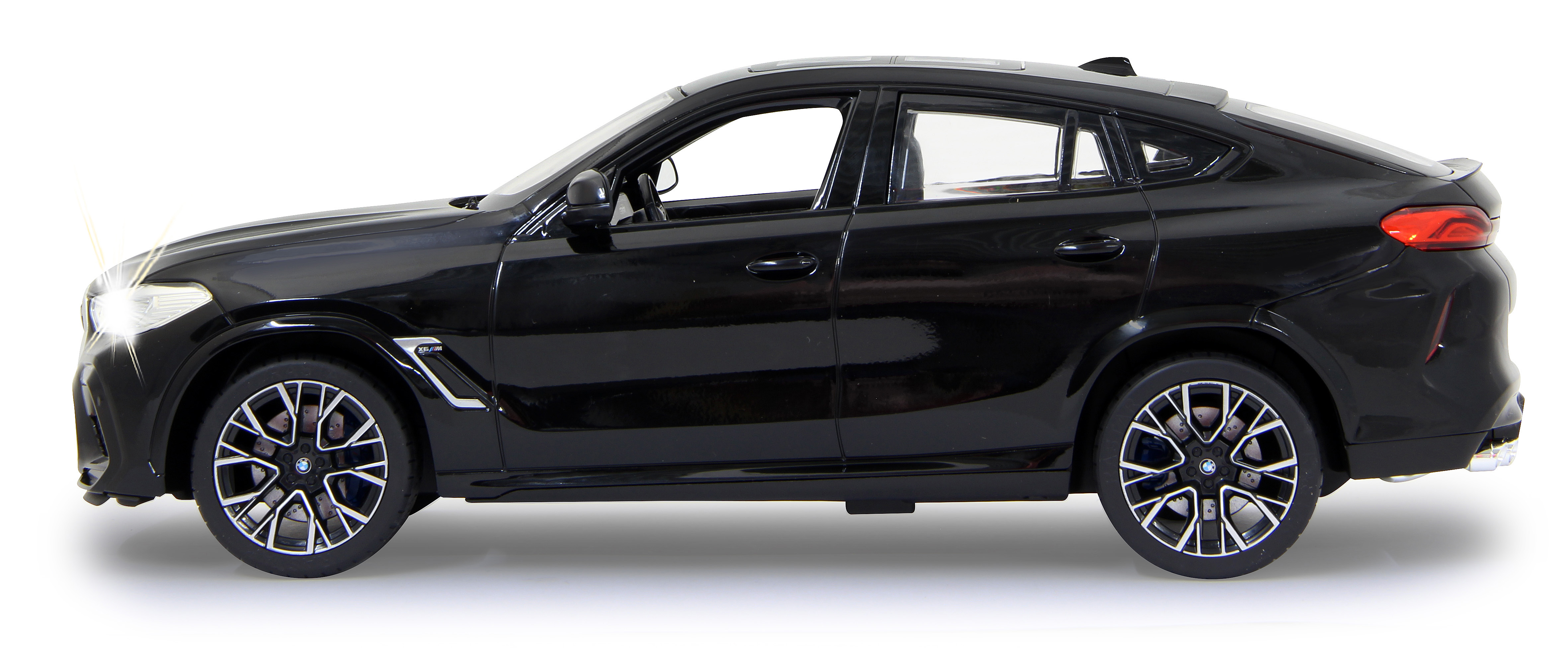 Schwarzes BMW X6 M Modellauto. Seitenansicht mit eingeschalteten Scheinwerfern. Weißer Hintergrund.