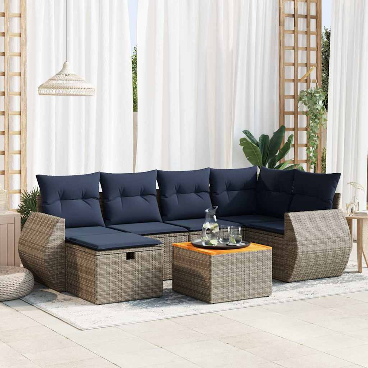 Ein graues Korbmöbel-Set mit blauen Kissen und einem Holztisch.