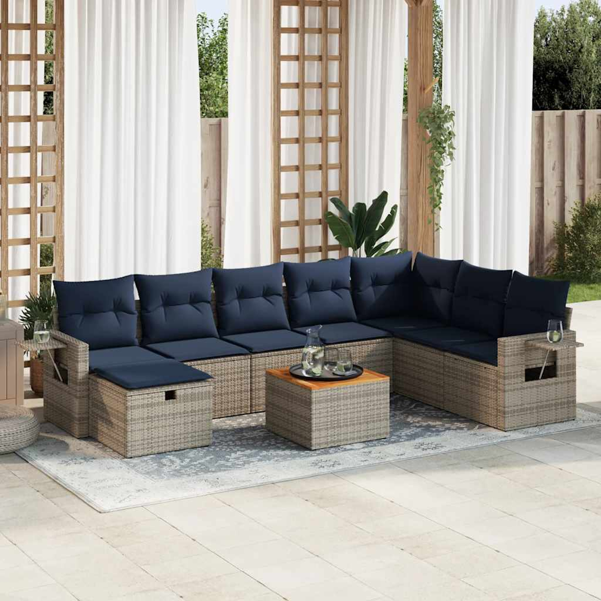 Rattan-Outdoor-Sofagarnitur mit blauen Kissen, Couchtisch und Beistelltischen mit Getränken. Weiße Vorhänge.