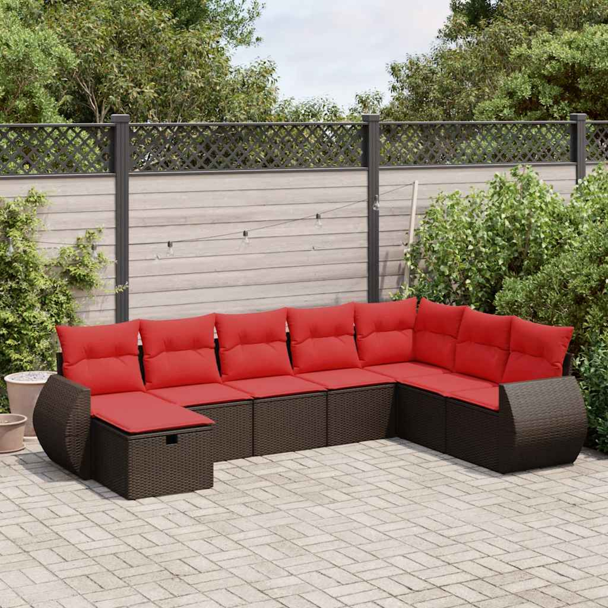 Ein Outdoor-Ecksofa mit roten Kissen und einer Ziegelterrasse vor einem Zaun.