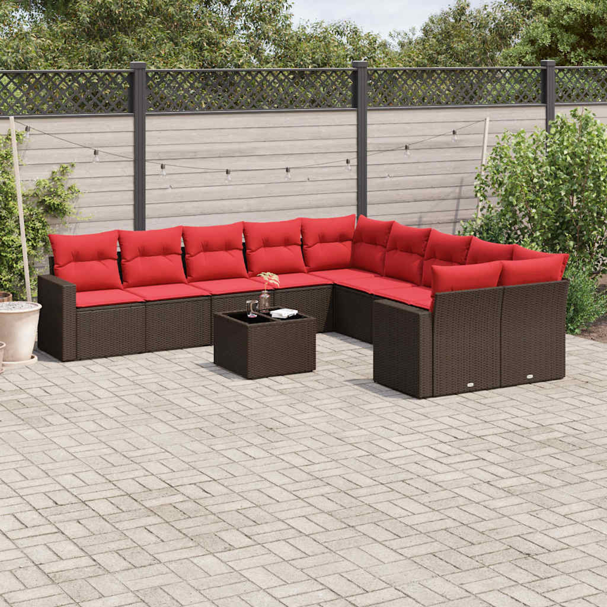 Ecksofa für den Außenbereich mit roten Kissen. Das Sofa ist braun, davor steht ein kleiner Tisch.