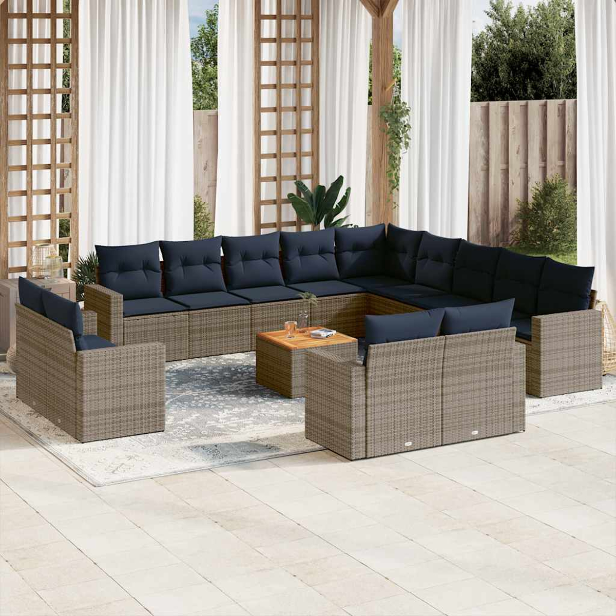 Garten-Rattanmöbel-Set mit marineblauen Kissen, Tisch und Teppich, in einer Gartenszene mit weißen Vorhängen.