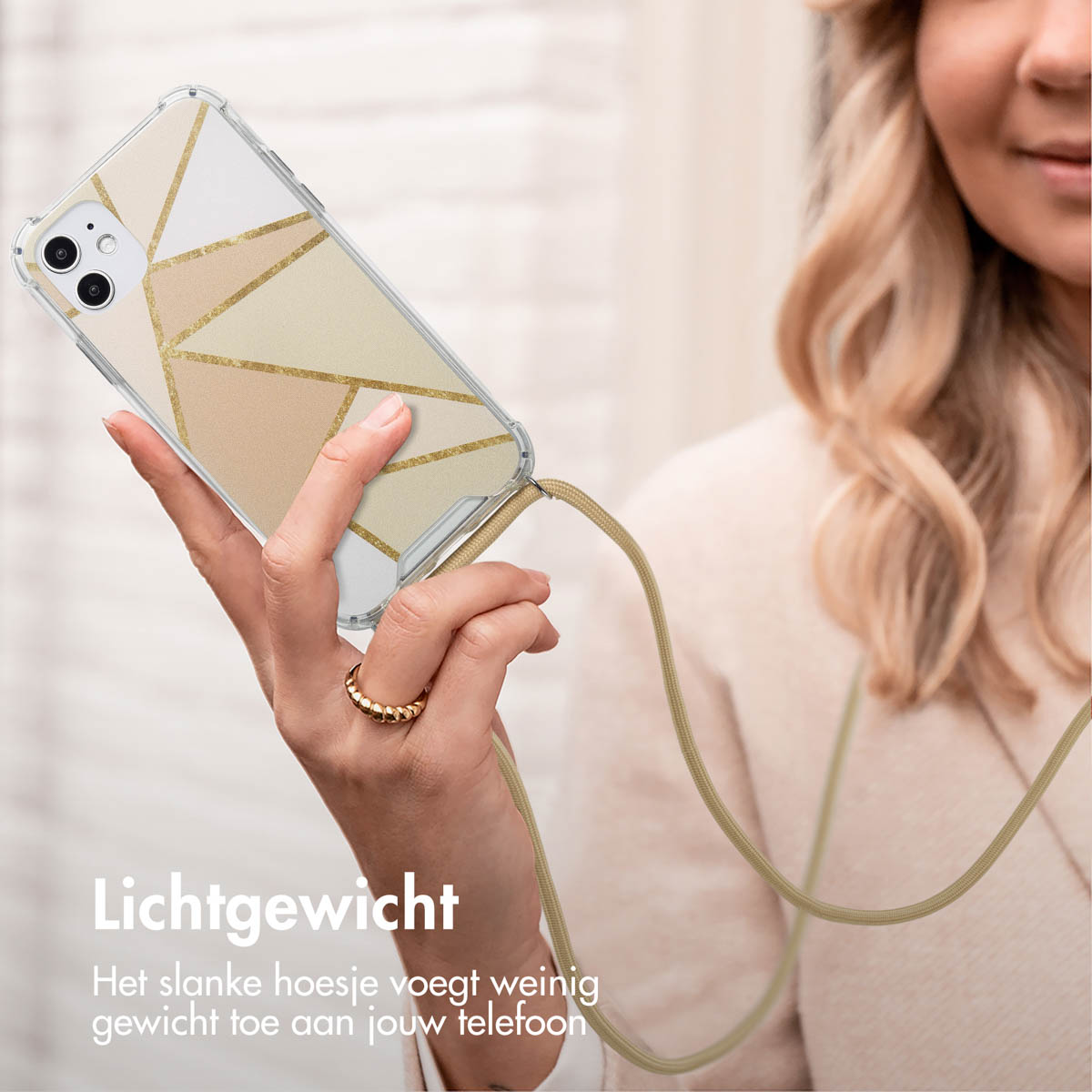 La main d'une femme tenant un téléphone avec une coque au design géométrique. Il y a un cordon.