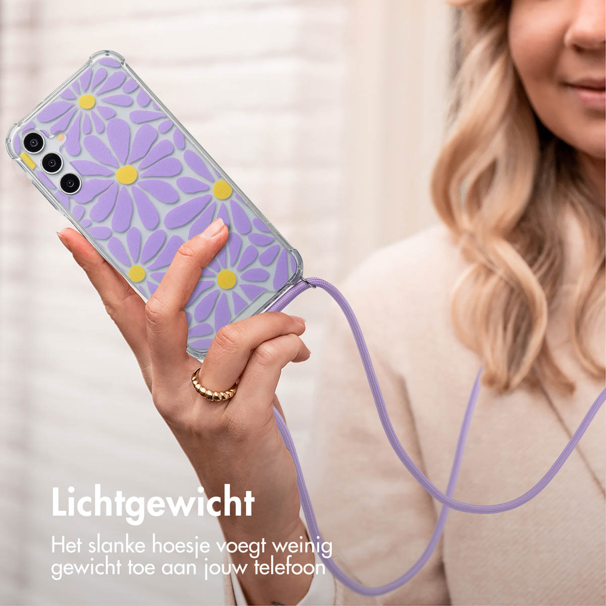Een persoon die een telefoon vasthoudt met een hoesje met madeliefpatroon en een lavendelkleurig koord.