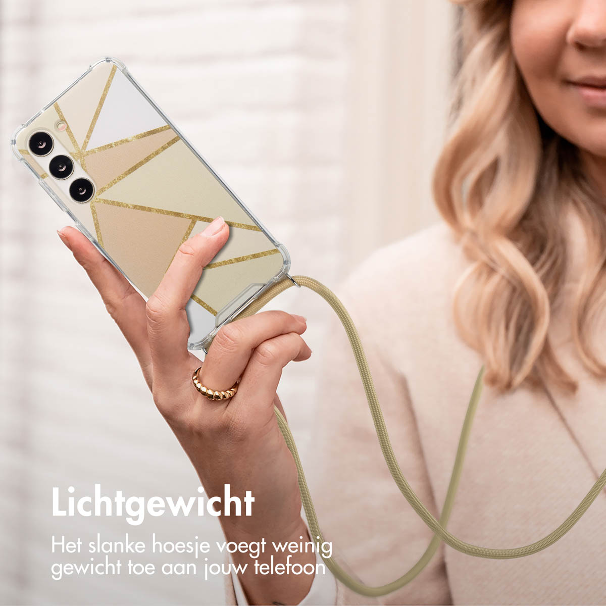 Vrouw houdt een telefoon vast met een doorzichtige hoes en gouden design met een koord.
