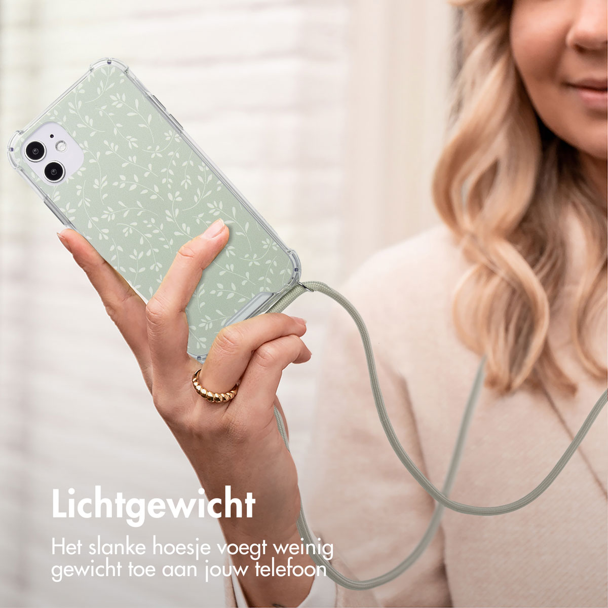 Femme tenant un téléphone dans une coque transparente avec un motif floral et une lanière.