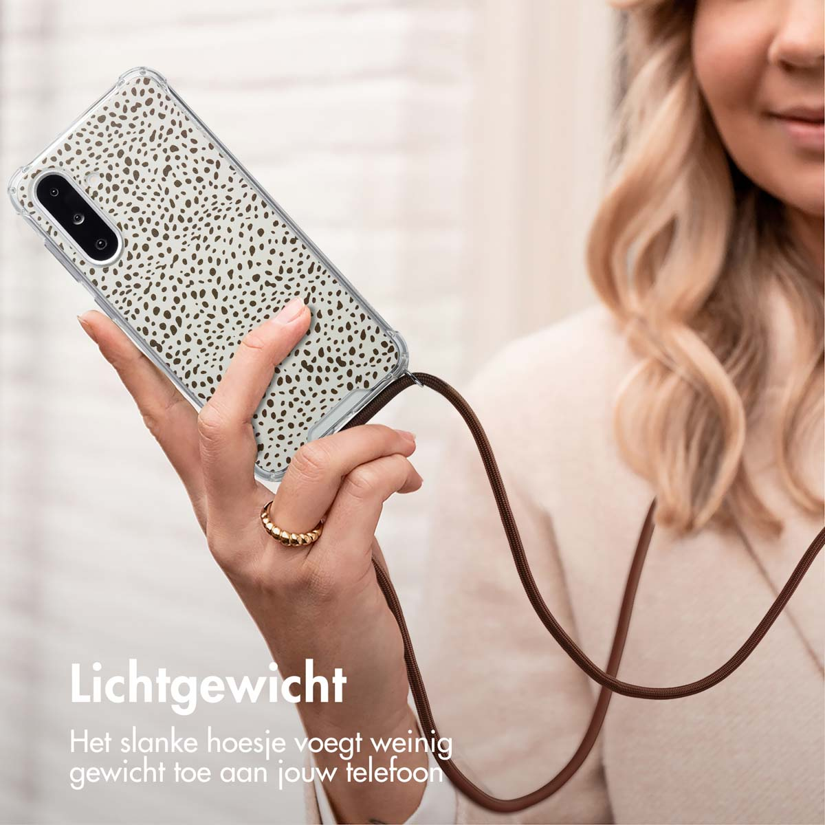 Een vrouw die een telefoon vasthoudt met een patroonhoesje en een bruin koord. Tekst: 'Lichtgewicht'.