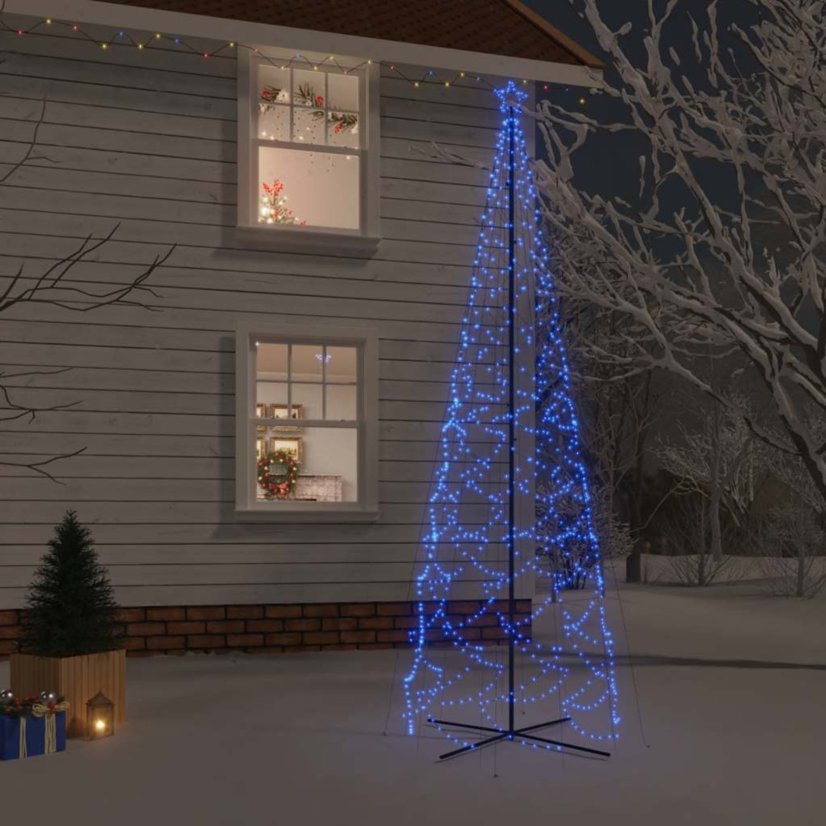 Weihnachtsbaum mit blauen Lichtern vor einem Haus. Schnee bedeckt den Boden.