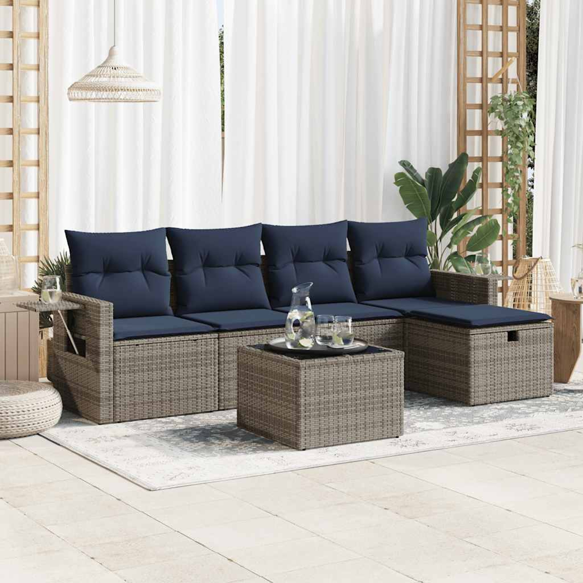 Ein Terrassenset mit Sofa, Tisch und Fußstütze. Das Sofa hat blaue Kissen. Der Hintergrund ist ein weißer Vorhang.