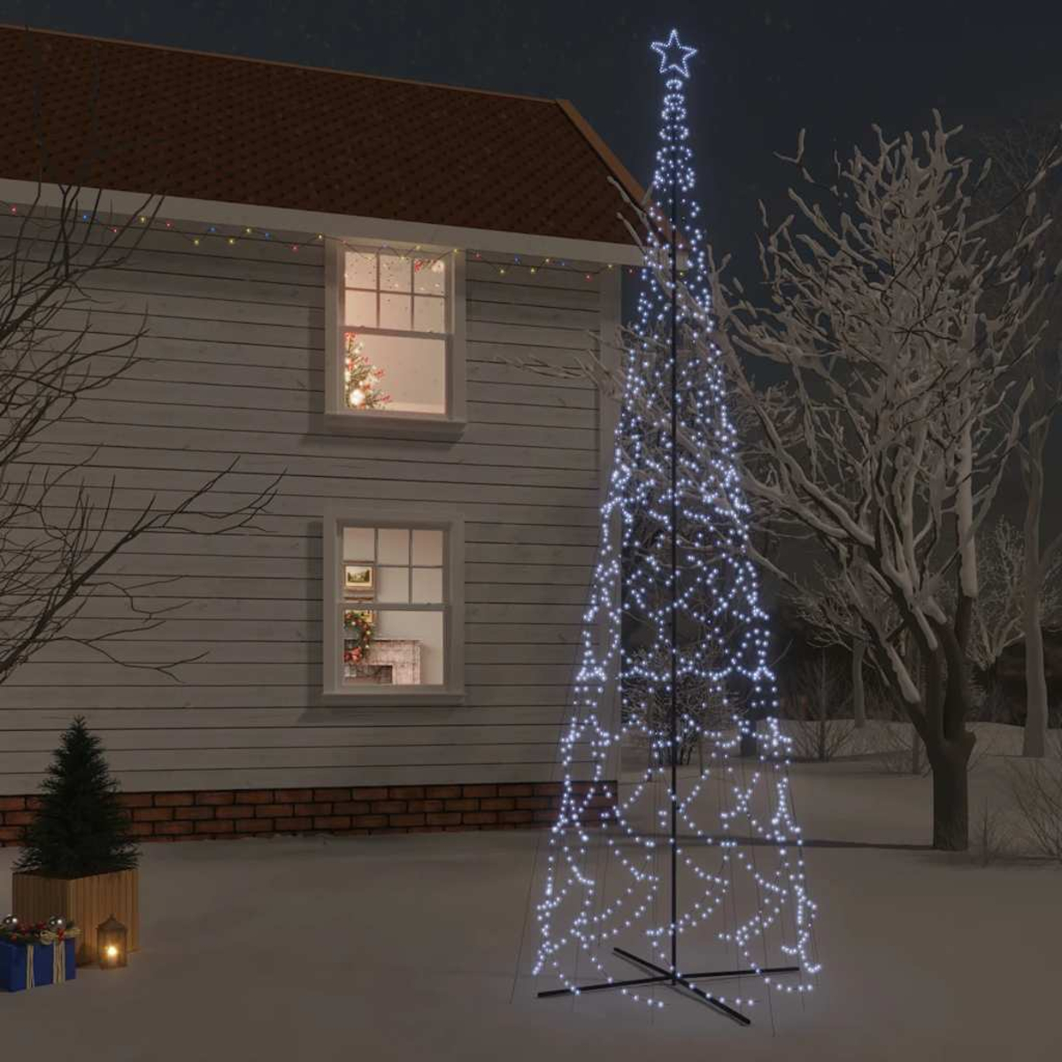 Ein beleuchteter Weihnachtsbaum vor einem Haus bei Nacht. Stern oben. Schnee im Garten.