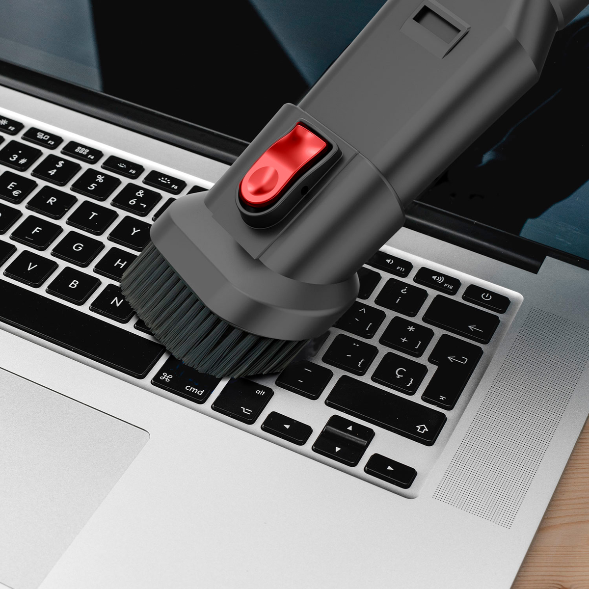 Un teclado de portátil que se limpia con un accesorio de cepillo conectado a una aspiradora.