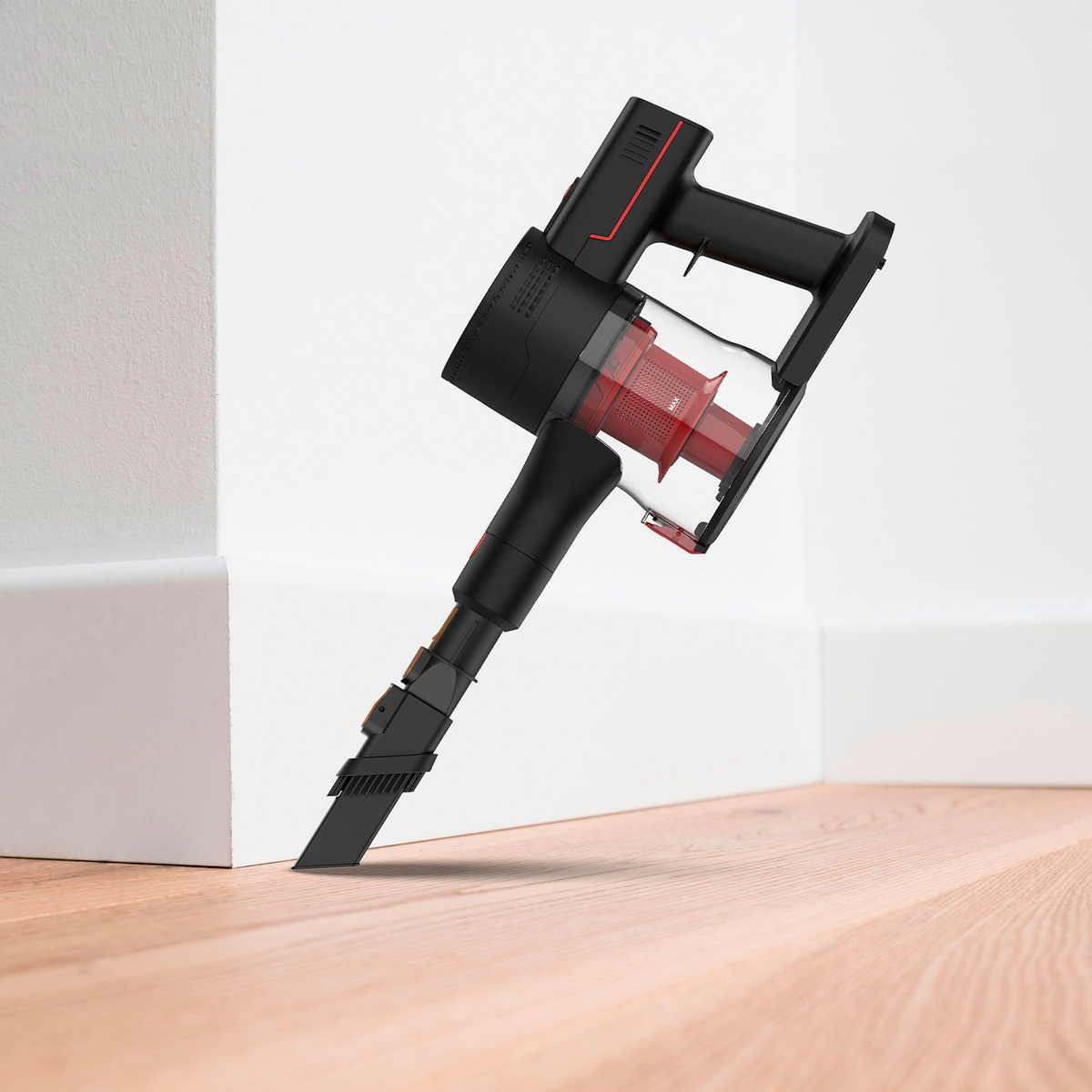 Aspiradora inalámbrica negra y roja contra pared blanca y suelo de madera, mostrando el accesorio de cepillo.