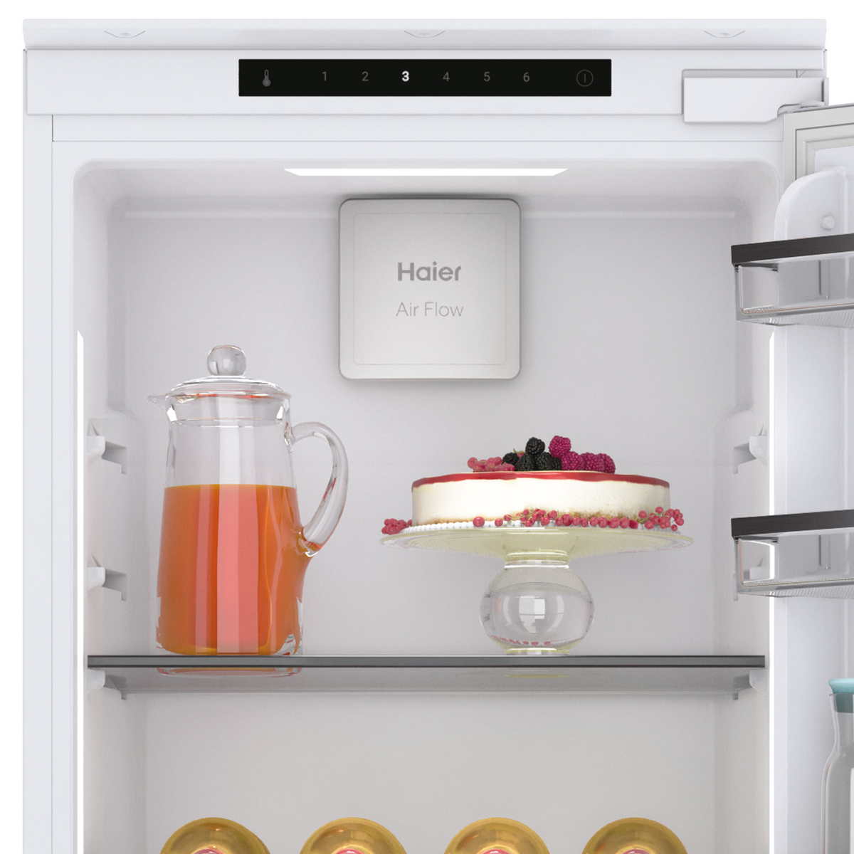Primer plano del interior de un refrigerador blanco. Se ve una jarra de jugo y un pastel. Fondo blanco.