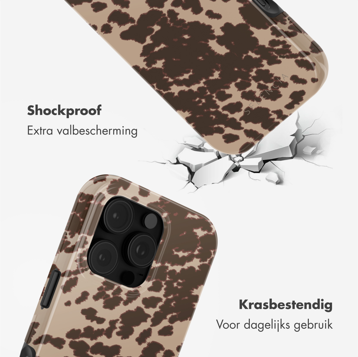 Een telefoon in een hoesje met koeienprint. De hoes is gebarsten op een wit oppervlak.