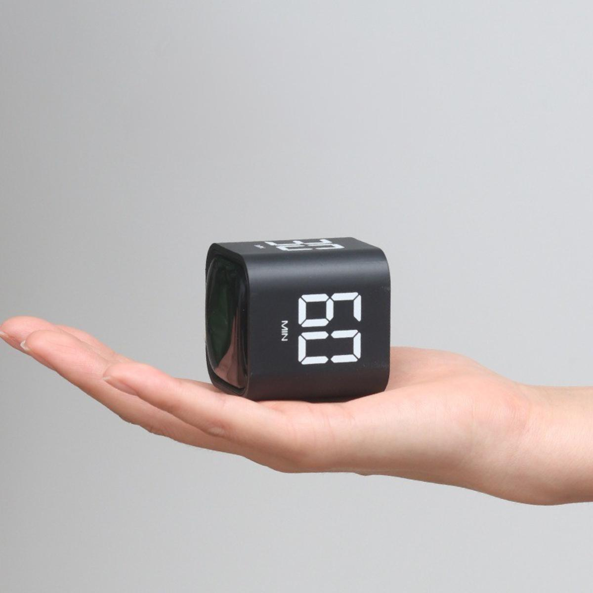 Schwarzer digitaler Würfel-Timer wird in einer Hand gehalten. Zeigt die Zahl 69 auf dem Bildschirm an.