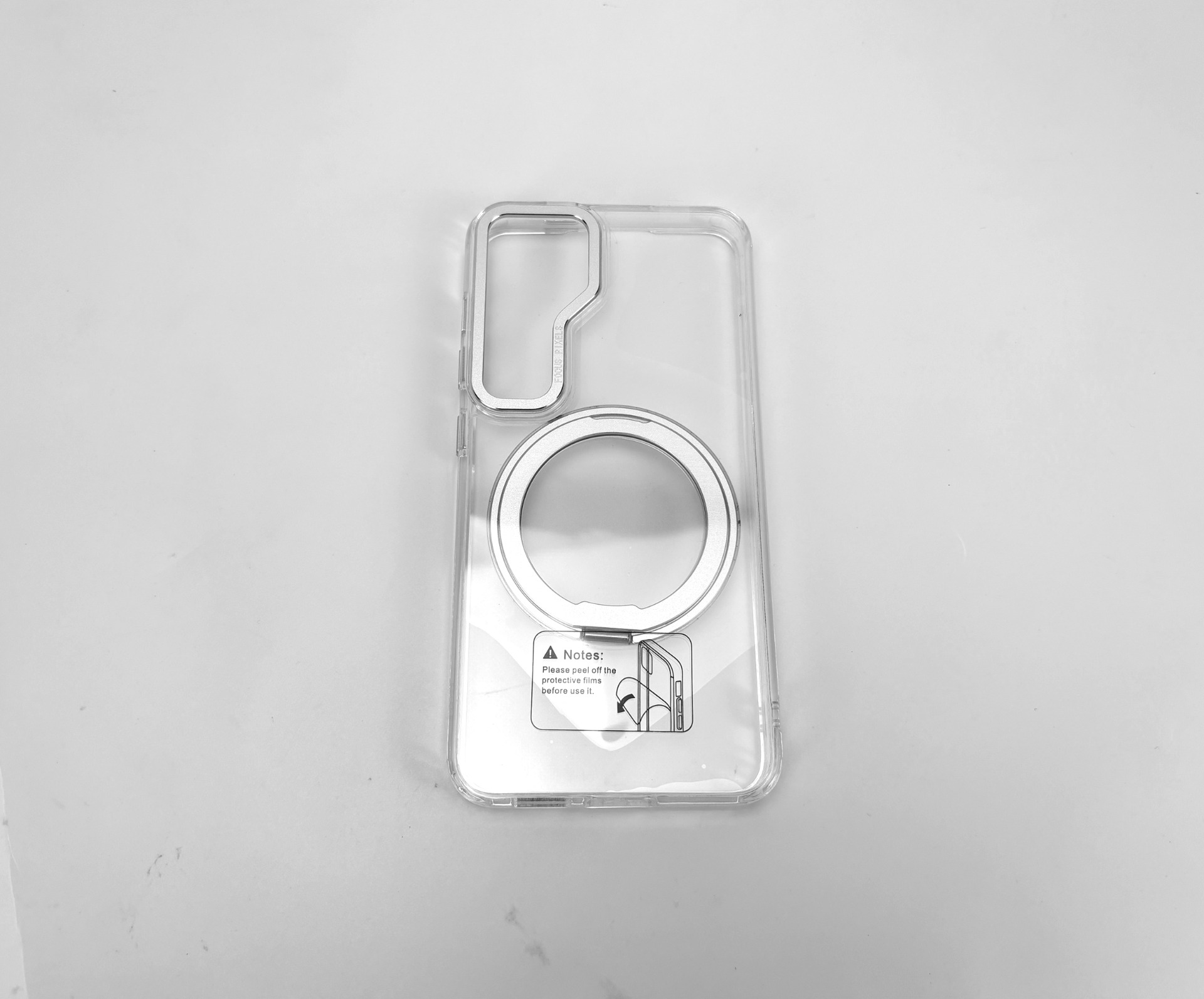 Transparente Handyhülle mit silbernem Ring und Aufkleber auf weißer Oberfläche.
