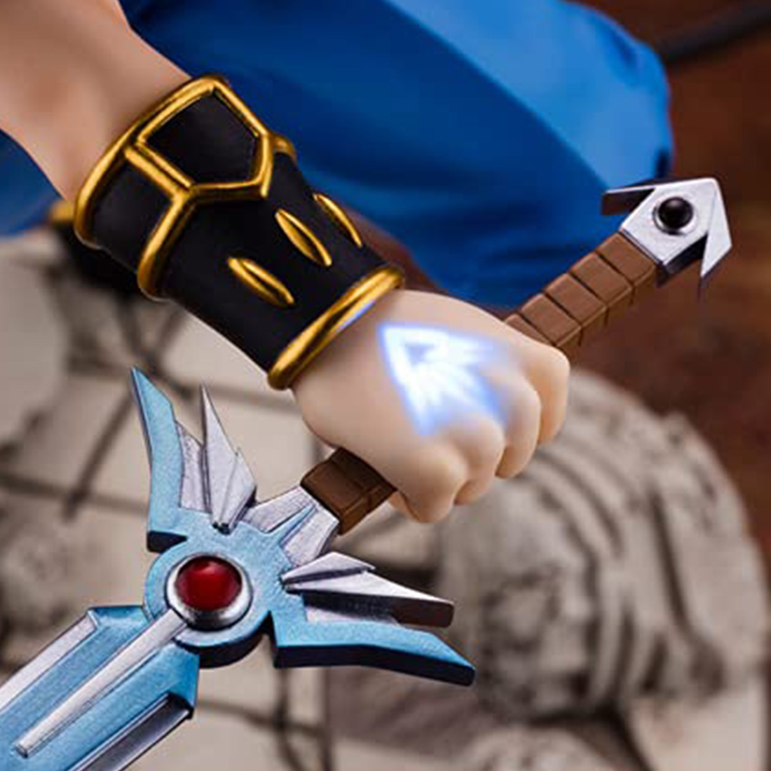 Nahaufnahme der Hand einer Figur, die ein Schwert mit einem blau leuchtenden Effekt auf der Klinge hält.