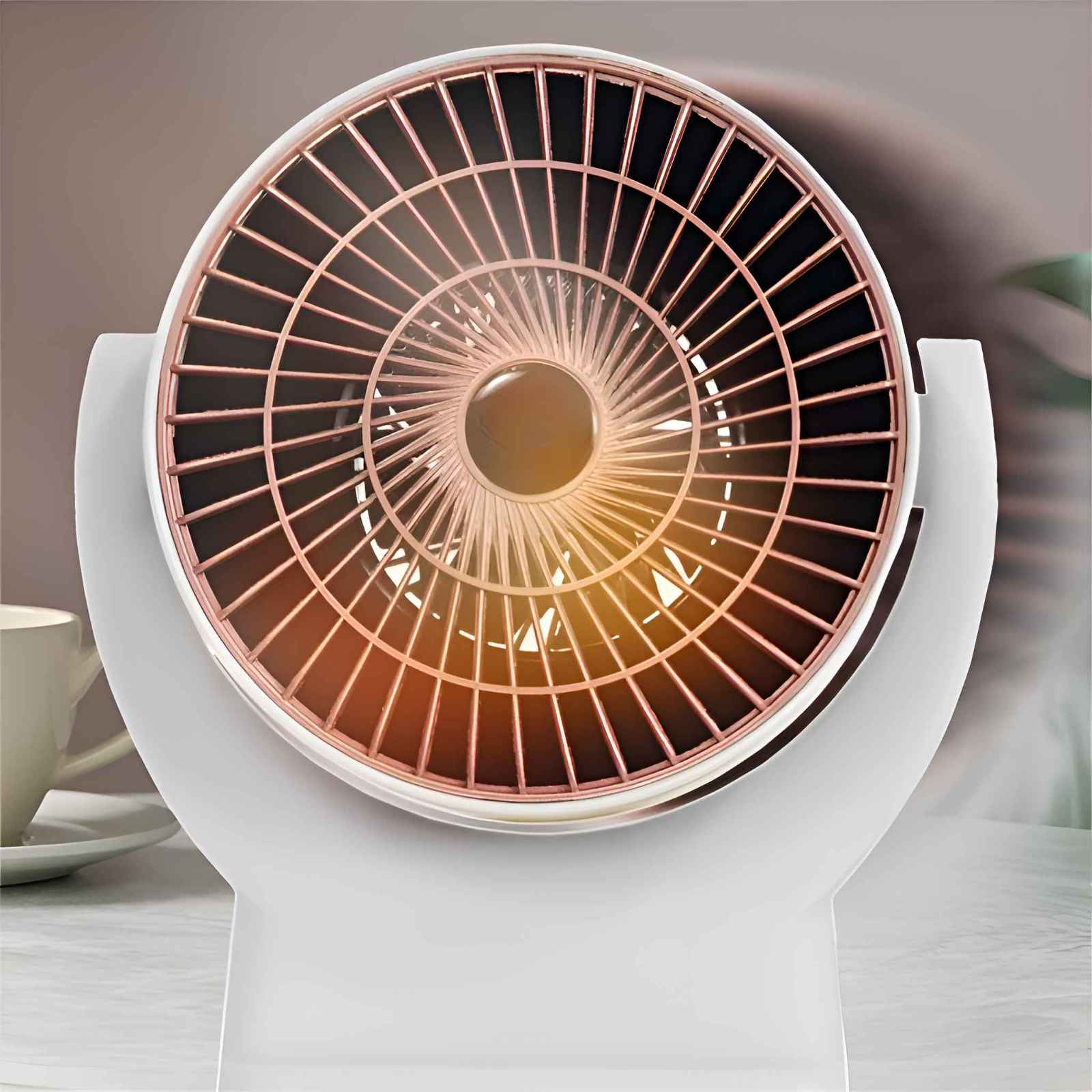 Ein weißer Ventilator mit roségoldenem Gitter. Der Hintergrund zeigt eine verschwommene Innenszene und eine Tasse.