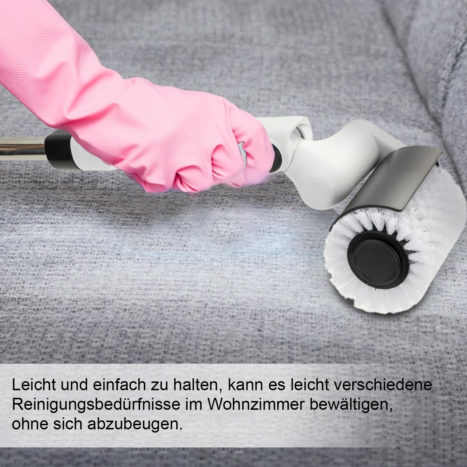 Eine Hand in einem rosa Handschuh benutzt eine Bürste, um ein graues Sofa zu reinigen.