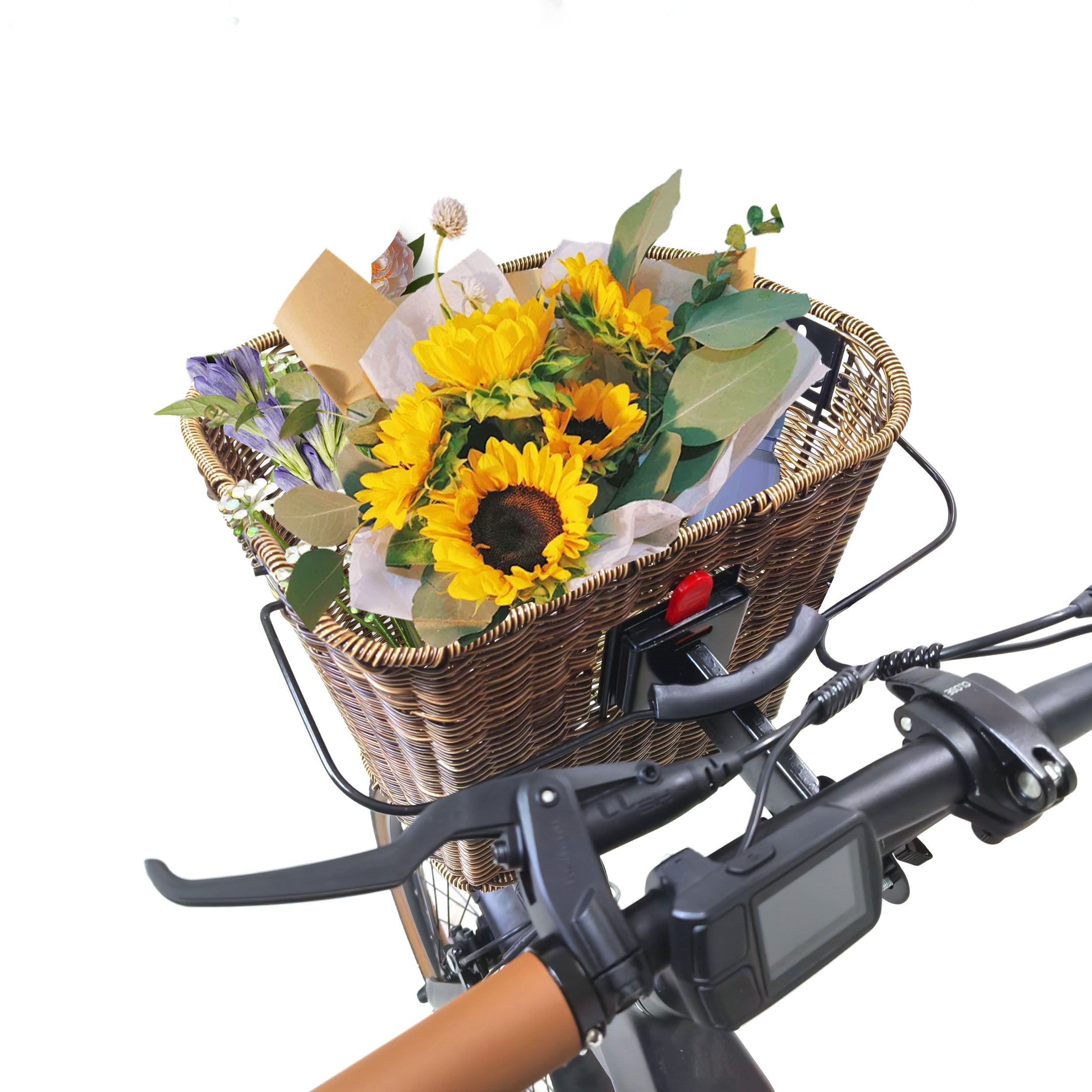 Ein Weidenkorb gefüllt mit Sonnenblumen und anderen Blumen an einem Fahrradlenker. Der Lenker hat Bedienelemente.