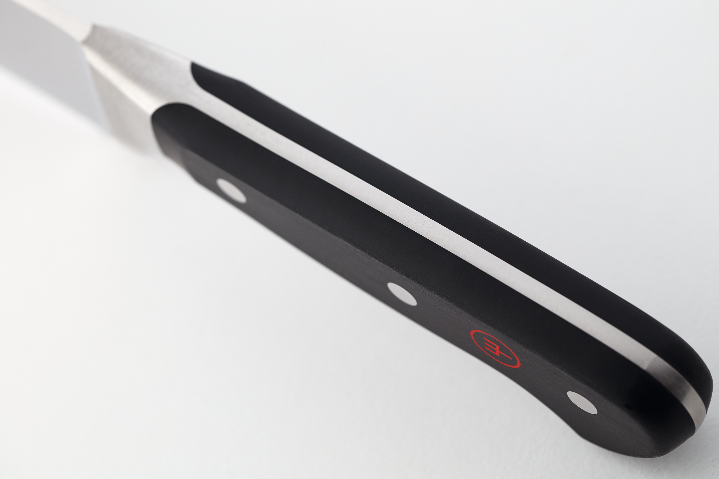 Primer plano de un mango de cuchillo. Mango negro con detalles plateados y un logotipo rojo.