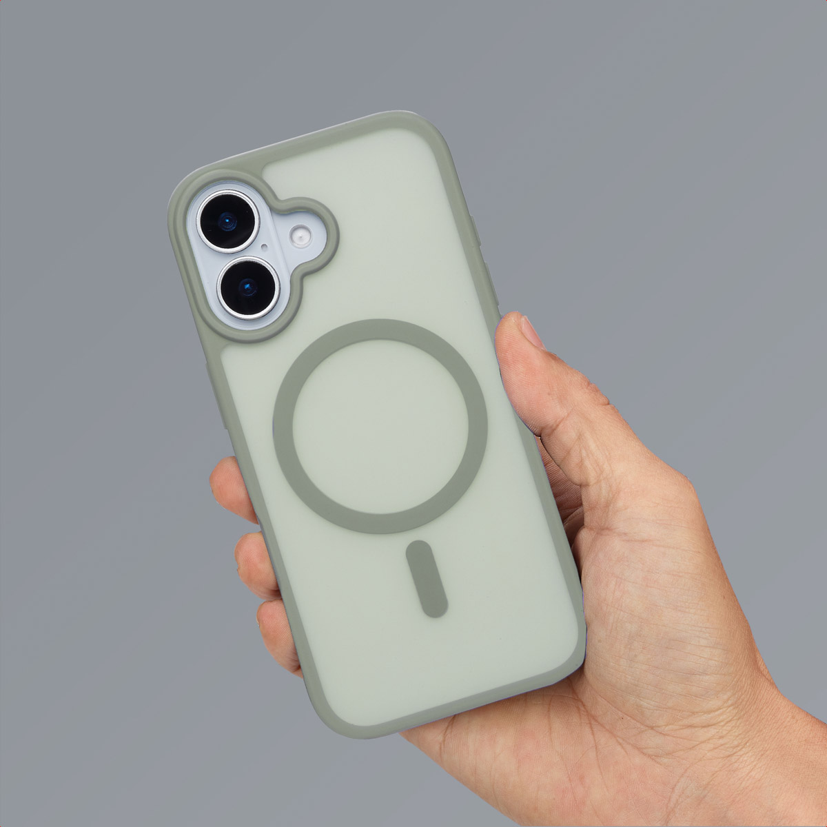 Een hand houdt een groen telefoonhoesje vast. De hoes heeft een magnetische ring. De achtergrond is grijs.