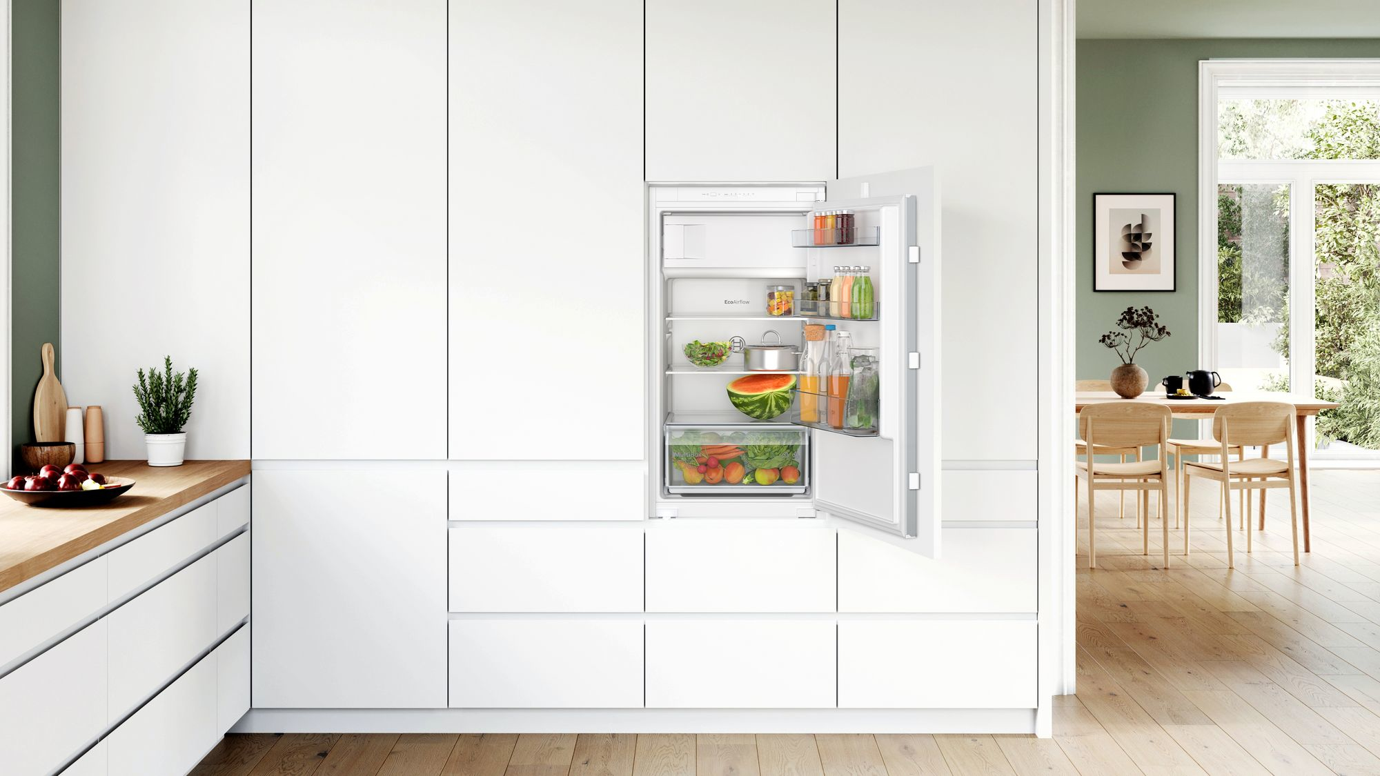 Ein Kühlschrank in einer weißen Küche installiert. Die Tür ist geöffnet.