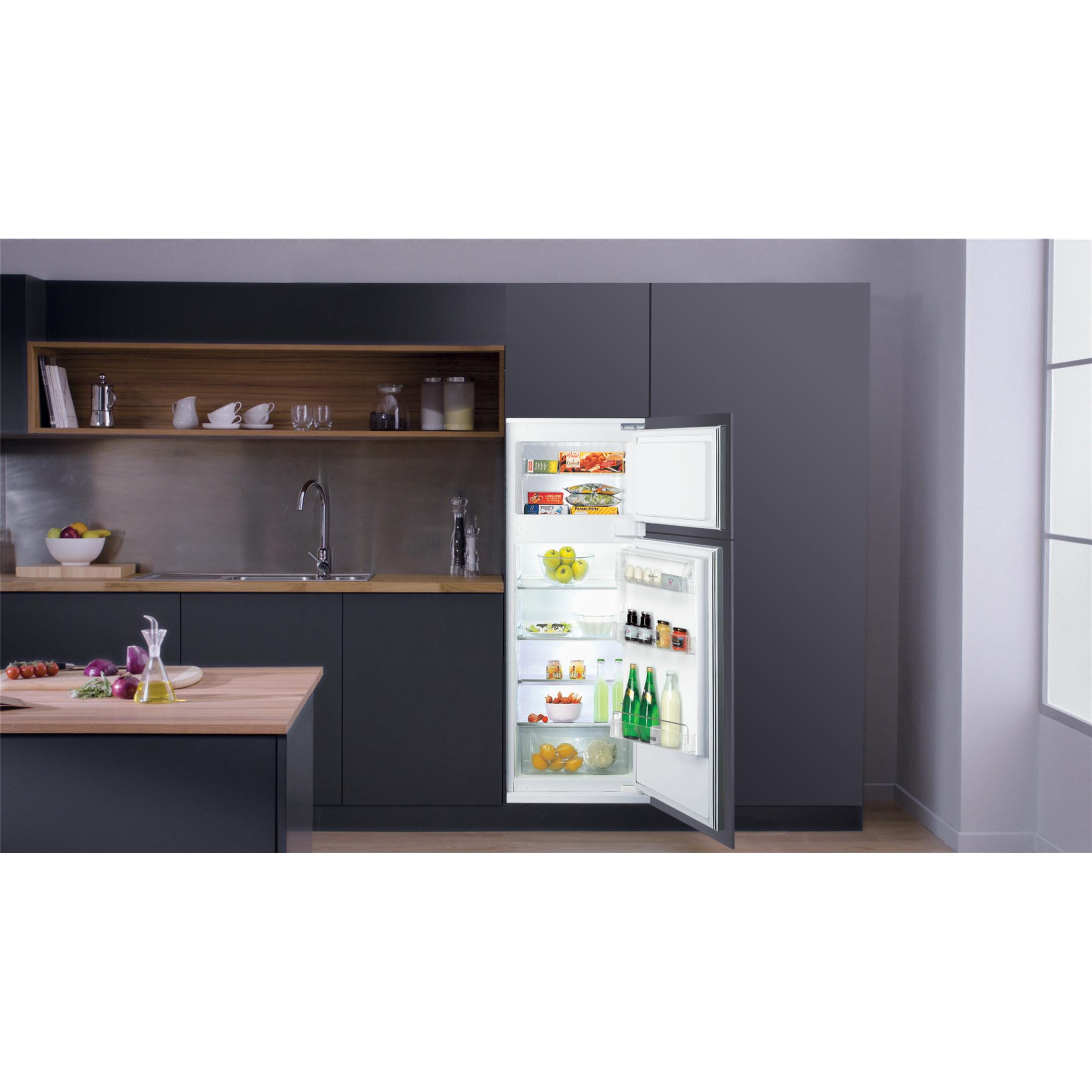 Ein weißer Kühlschrank in einer Küche eingebaut. Der Kühlschrank ist geöffnet und mit Lebensmitteln gefüllt.