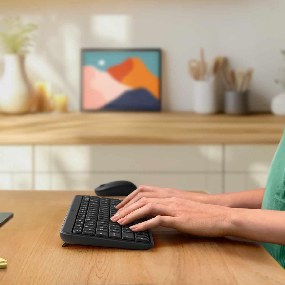 Le mani di una donna che digitano su una tastiera nera su un tavolo di legno. Un mouse è accanto.