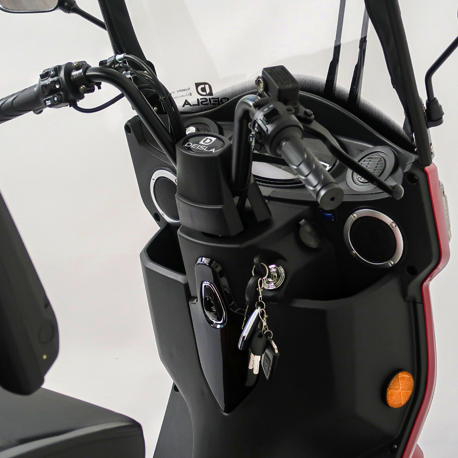 Nahaufnahme des Lenkers, Armaturenbretts und der Schlüssel eines Rollers. Schwarzes und rotes Farbschema dominiert.