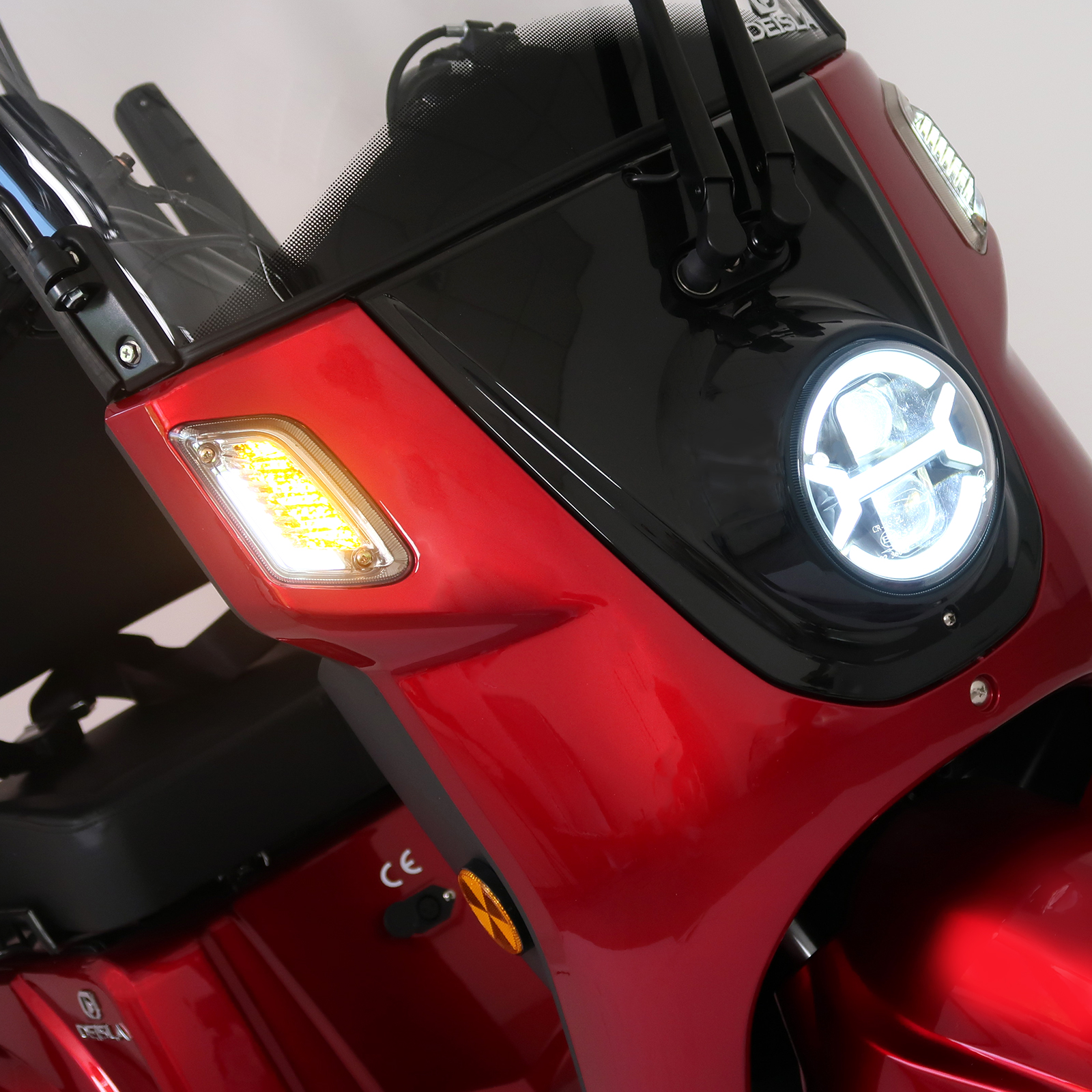 Nahaufnahme der roten Mobilitätsroller-Front. Scheinwerfer und Blinker sind sichtbar, mit einer schwarzen Front.